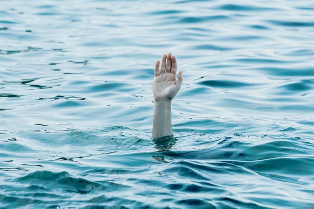 Eine Hand, die den Ozean, das Rettungs- und Hilfekonzept, die Selbstpflege, das Ertrinken von Angst und das konzeptionelle Bild von Problemen, den Kopierraum zeigt