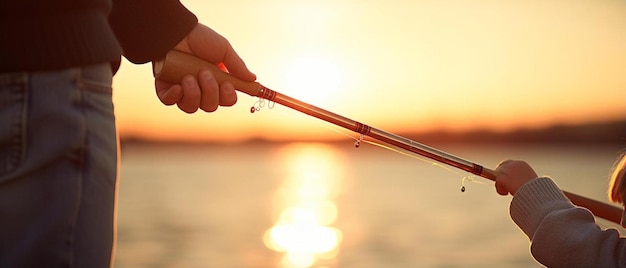 eine Hand, die eine Fischstange mit der Sonne dahinter hält