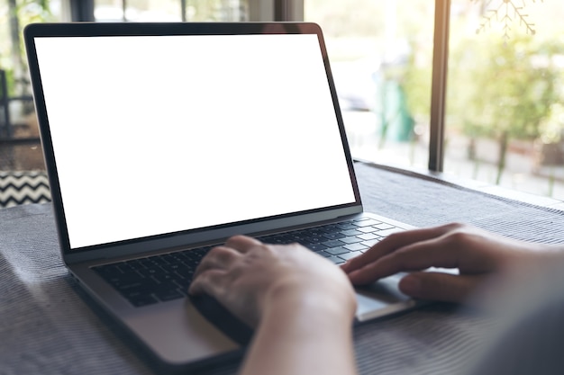 eine Hand, die Laptop mit leerem weißem desktop-Bildschirm auf Tabelle im Café verwendet und berührt