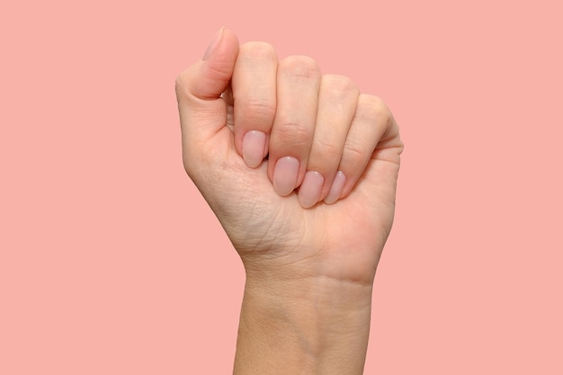 Eine Hand einer jungen schönen Frau. Natürliche Maniküre. Auf einem rosa Hintergrund.