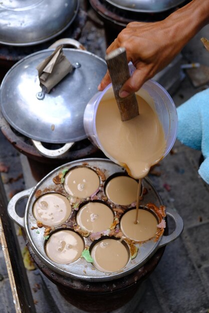 Foto eine hand gießt carabikang-teig in eine eisenform. carabikang ist ein traditionelles lebensmittel aus reis