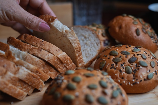 Eine Hand greift nach einer Scheibe Brot, auf der noch ein paar andere Brote liegen.