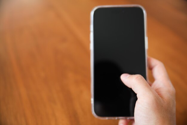 Eine Hand hält ein Telefon mit schwarzem Bildschirm.