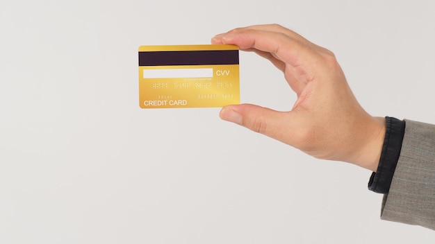 Eine Hand hält goldene Kreditkarten zurück und trägt einen Anzug auf weißem Hintergrund.