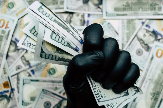 Eine Hand in einem schwarzen Handschuh hält Dollarnoten