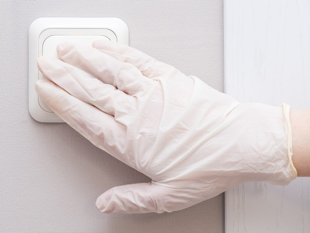 Eine Hand in sterilen Gummihandschuhen macht das Licht zu Hause oder im Krankenhaus an.