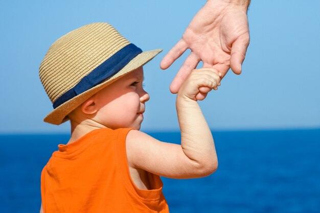 Eine Hand von Kind und Eltern im Urlaub am Meer.