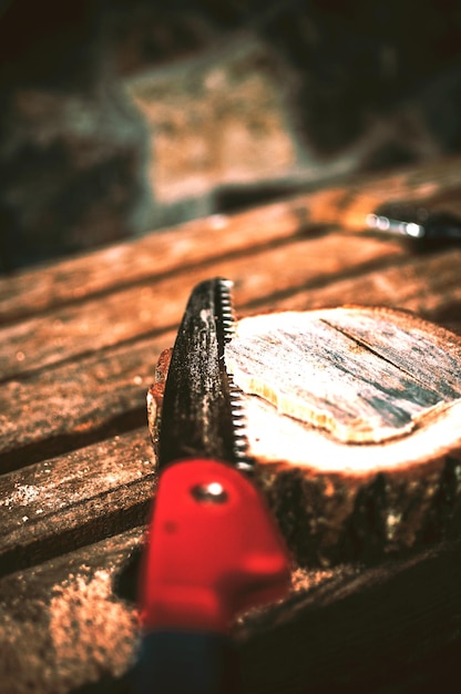 Eine Handsäge schneidet ein Stück Holz von einem Rundbalken und Kiefern auf einer Bank Rund um die Trümmer und Sägespäne Ein Holzständer für Lebensmittel für das Meisterklassen-DIY-Konzept