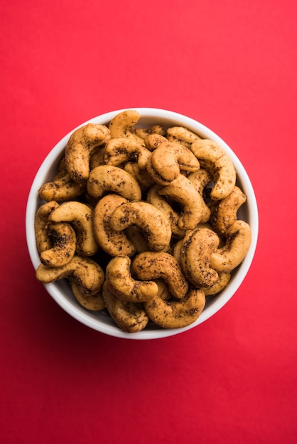 Eine Handvoll geröstete gewürzte Cashewnüsse oder Masala Kaju, serviert in einer Schüssel, selektiver Fokus