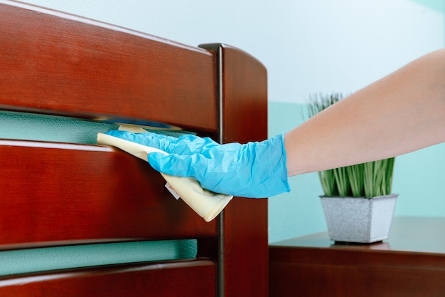 Eine Hausfrau im Hemd putzt das Haus, wischt mit einem Putzlappen Staub vom Tisch
