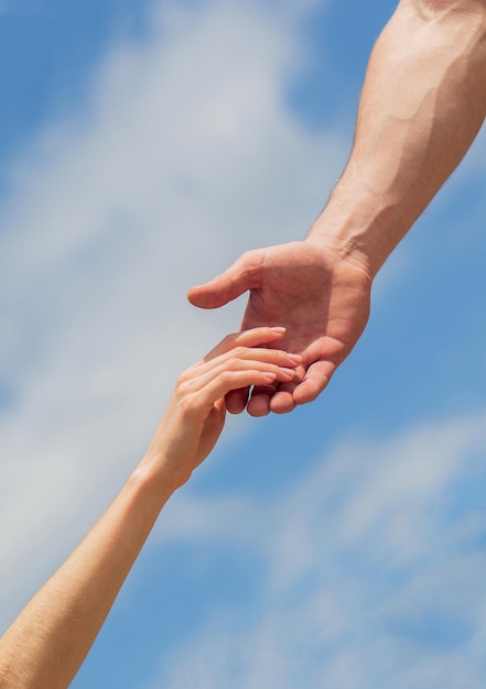 Eine helfende Hand geben Hände von Mann und Frau auf blauem Himmelshintergrund Eine helfende Hand verleihen Solidarität, Mitgefühl und Wohltätigkeitsrettung