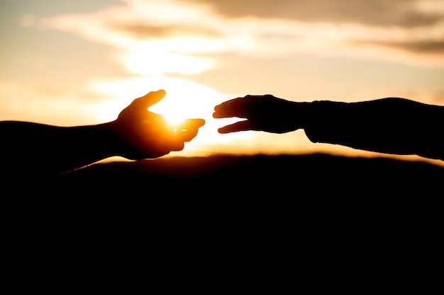 Eine helfende Hand geben. Helfende Geste oder Hände zur Rettung. Silhouette mit zwei Händen auf Himmelshintergrund. Verbindung oder Hilfekonzept. Ausgestreckte Hände. Rettung. Hilfe. Silhouette-Konzept. Hilfe