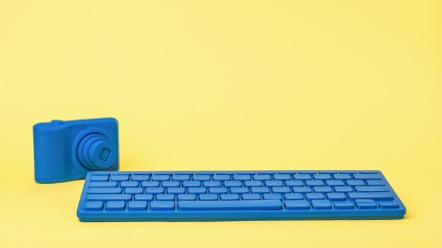 Eine hellblaue Tastatur und eine hellblaue Kamera auf einem gelben Hintergrund. Stilvolles Zubehör für Geschäftsreisende und Freiberufler.