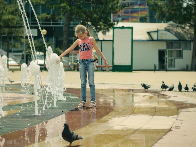 Eine herde von tauben, die um mädchen im stadtbrunnen hängen.