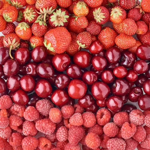 eine Himbeere, eine Kirsche und eine Erdbeere, Draufsicht. Gemischte Beeren