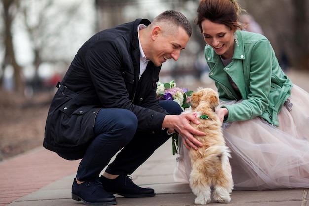 Eine Hochzeit von ein paar jungen Leuten. Sie sind glücklich und jung und genießen diesen Tag mit ihrem süßen Hund. Sinnliches Foto eines liebevollen schönen Mädchens und hübschen Kerls.