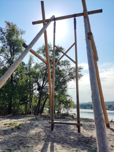 Eine hölzerne Schaukel ist im Park auf dem Sand in der Nähe der Bäume installiert.