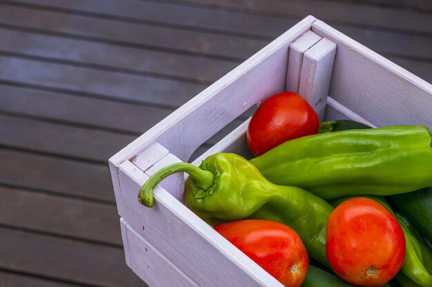 Eine Holzkiste voller reifer Paprika und Pflaumentomaten