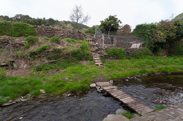 Eine Holzplankenbrücke, um den Fluss Arrago zu überqueren und den Bio-Garten und den Hühnerstall zu erreichen