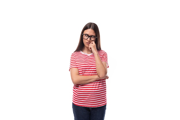 Eine hübsche einjährige europäische Dame in einem roten gestreiften T-Shirt trägt eine Brille zur Sehkorrektur auf einem weißen