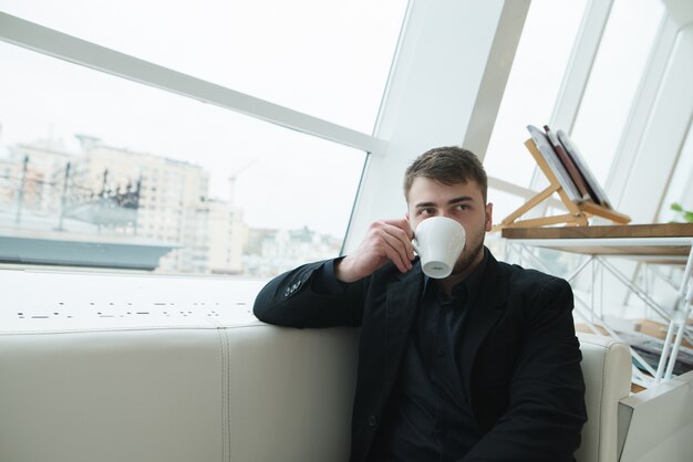 Eine hübsche Geschäftsfrau, die in einem Café am Fenster sitzt und Kaffee trinkt. Kaffeepause im stilvollen modernen Café