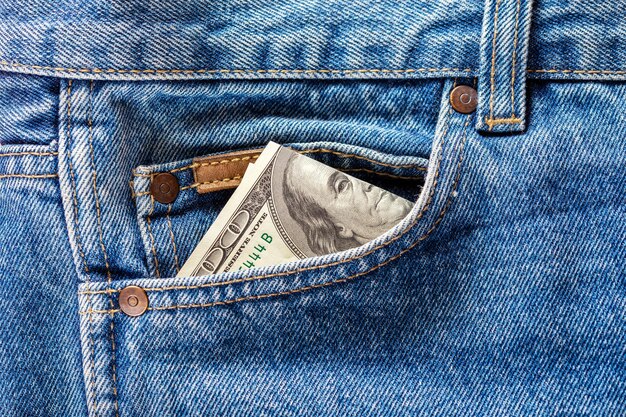 Eine hundert-Dollar-Banknote, die aus der Vordertasche der Jeans herausragt