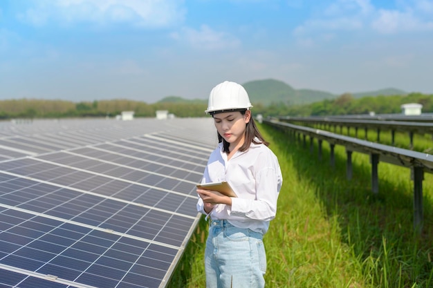 Eine Ingenieurin mit Helm in der Photovoltaik-Zellfarm oder im Solarpanels-Feld eco