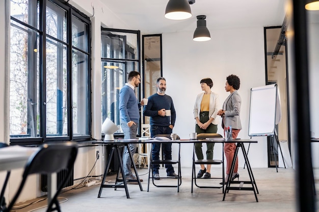 Eine interrassische Gruppe von Geschäftsleuten trinkt bei einer Kaffeepause im Büro Kaffee