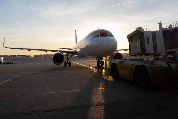 Eine Jet-Brücke, die bei Sonnenuntergang mit einem Flugzeug verbunden ist