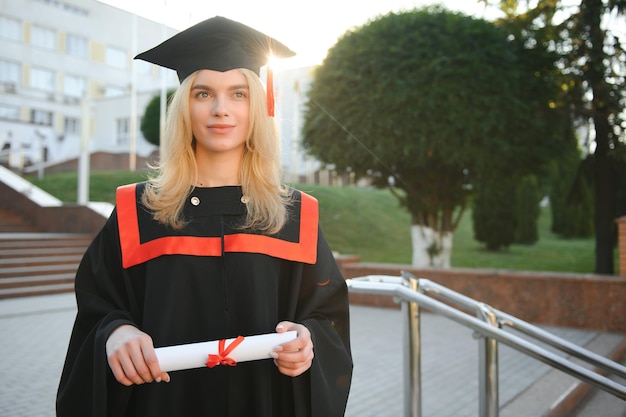 Eine junge Absolventin vor dem Hintergrund der Universität