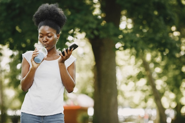 Eine junge Afroamerikanerin mit einem Telefon im Park