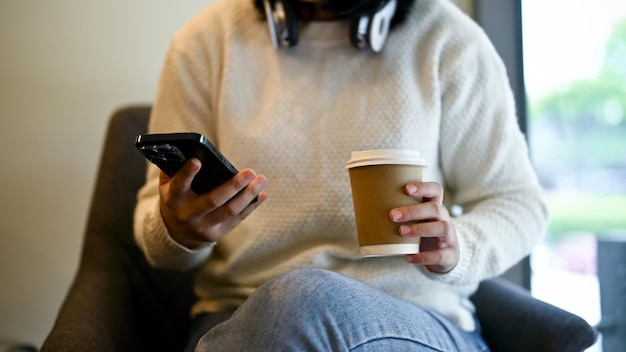 Eine junge Asiatin trinkt Kaffee und benutzt ihr Smartphone in einem Café