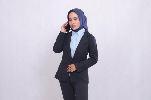Eine junge asiatische Bürocheffrau, die einen Hijab trägt, steht elegant, während sie jemanden auf ihrem C ruft