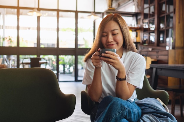 Eine junge asiatische Frau, die Kaffee im Café hält und trinkt