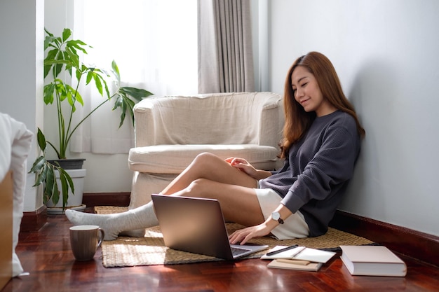 Eine junge asiatische Frau, die zu Hause einen Laptop verwendet und daran arbeitet