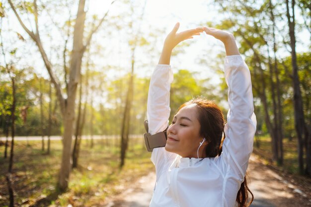 Eine junge asiatische Frau streckt die Arme, bevor sie im Stadtpark läuft