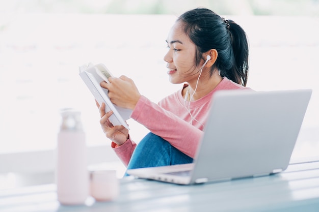 Eine junge asiatische freiberufliche Geschäftsfrau, die während der COVID-19-Pandemie zu Hause am Laptop arbeitet. Eine erwachsene Lernende, die online zu Hause lernt. Stock Foto