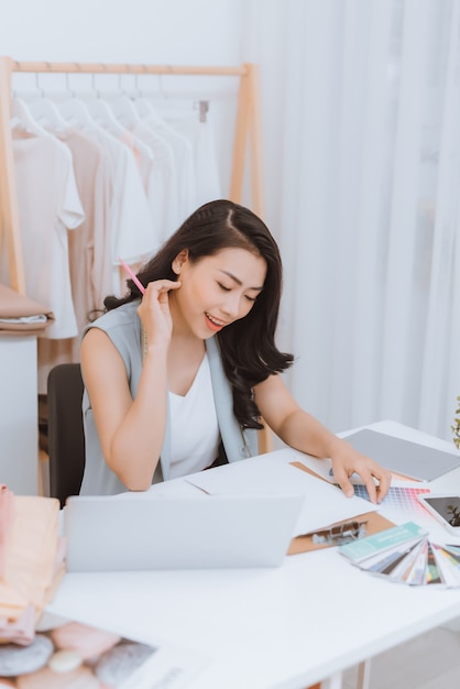 Eine junge asiatische Modedesignerin arbeitet an ihrem Atelier