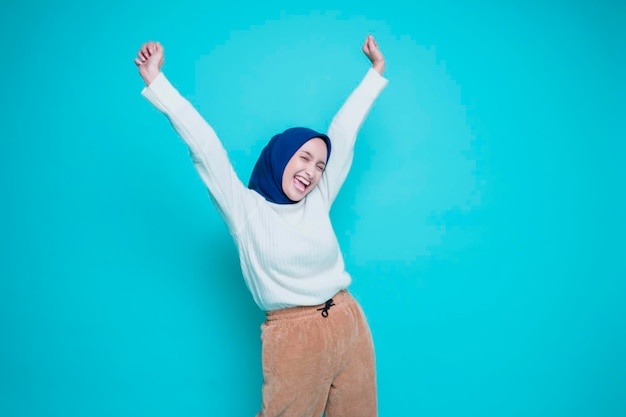 Eine junge asiatische muslimische Frau mit einem glücklichen, erfolgreichen Ausdruck, die ein weißes Hemd und Hijab trägt, isoliert durch weißen Hintergrund
