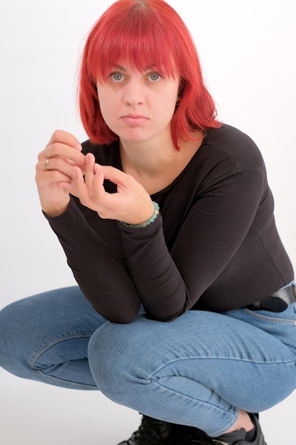 Eine junge attraktive Frau mit einer kurzen orangefarbenen Frisur in einem schwarzen T-Shirt auf weißem Hintergrund