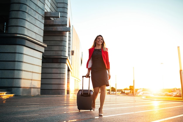 Eine junge berufstätige Frau, die am Flughafen ankommt und zu ihrem Auto geht