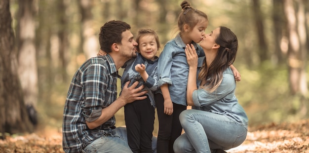 Eine junge Familie geht mit Kindern in den herbstlichen Wald.