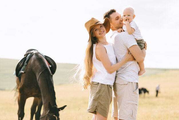 Eine junge Familie hat Spaß auf dem Feld. Eltern und Kind mit einem Pferd