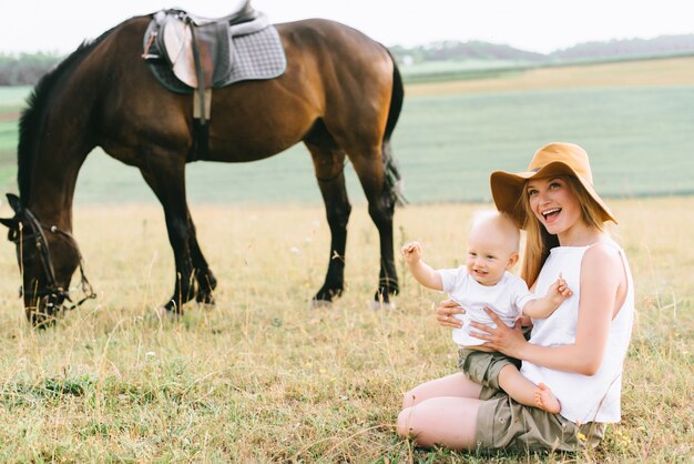 Eine junge Familie hat Spaß auf dem Feld. Eltern und Kind mit einem Pferd