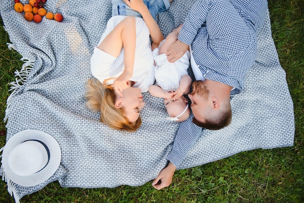 Eine junge Familie liegt auf einer Decke in einem Sommerpark