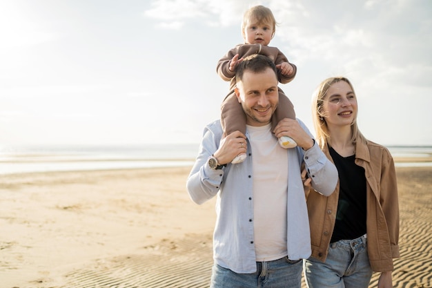 Eine junge Familie mit einem Kind, die einen freien Tag am Strand verbringen, glückliche Menschen zusammen