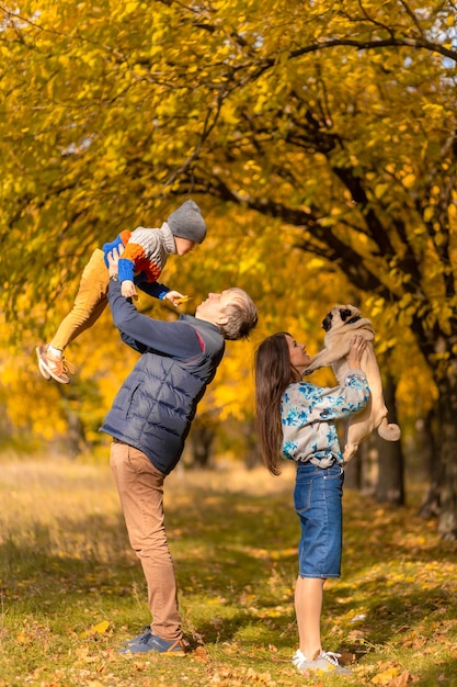 Eine junge Familie mit einem kleinen Kind und einem Hund verbringt gemeinsam Zeit für einen Spaziergang im Herbstpark.