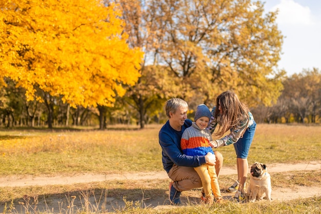 Eine junge Familie mit einem kleinen Kind und einem Hund verbringt gemeinsam Zeit für einen Spaziergang im Herbstpark