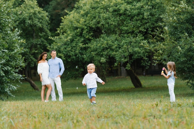 Eine junge Familie mit Sohn und Tochter entspannen sich im Sommer im Park Sie blasen Seifenblasen