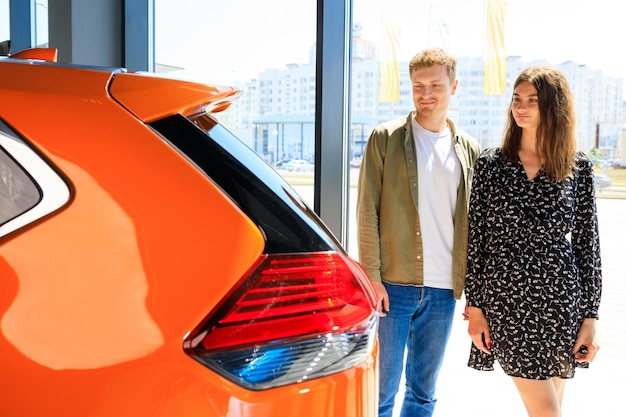 Eine junge Familie steht in einem Autohaus vor einem Auto. Schwierige Wahl eines Familienautos